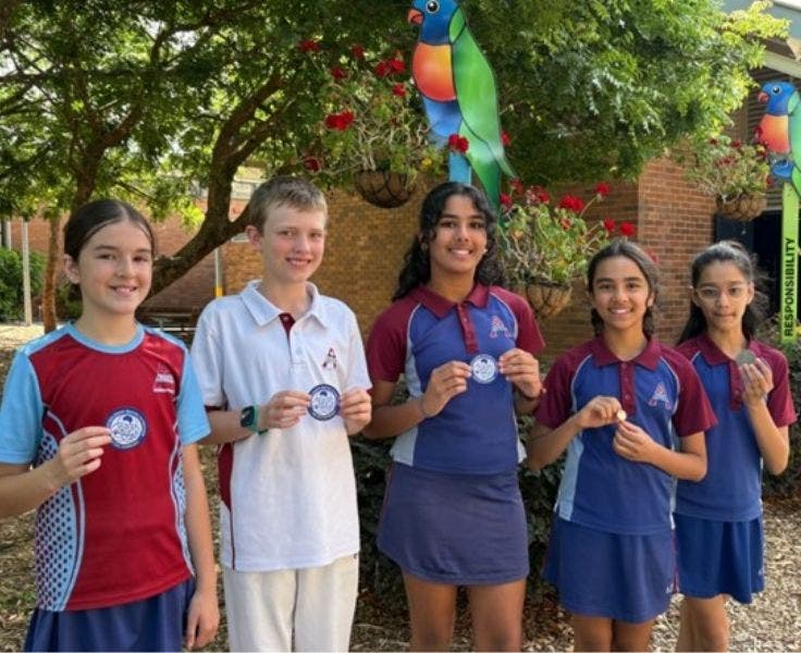Four female students and one male student displaying medals