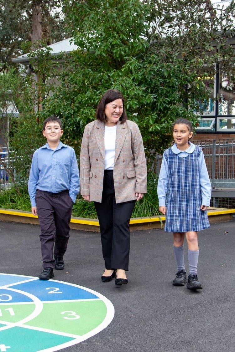 Principal walking with two students on playground